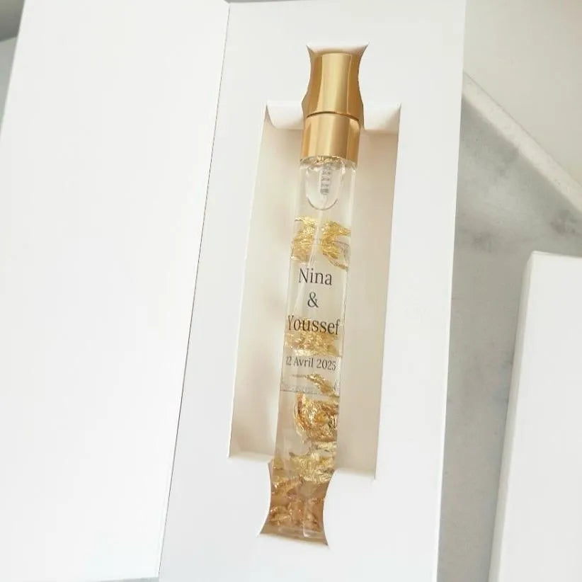Musc royal personnalisé avec éclats d'or dans un flacon élégant, présenté en coffret blanc raffiné.
